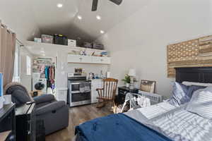 Bedroom featuring washer / clothes dryer, lofted ceiling, hardwood / wood-style flooring, ceiling fan, and a closet