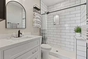 Bathroom featuring vanity, toilet, and curtained shower