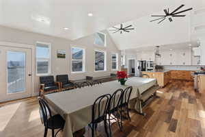 Dining room with ceiling fan, high vaulted ceiling, sink, and light hardwood / wood-style flooring