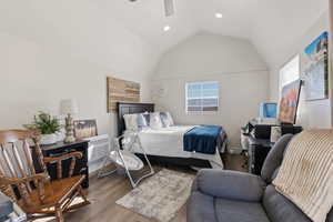 Bedroom with multiple windows, wood-type flooring, lofted ceiling, and a wall mounted air conditioner