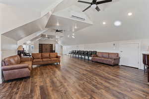 Living room featuring ceiling fan, lofted ceiling, dark hardwood / wood-style flooring, and a wall unit AC