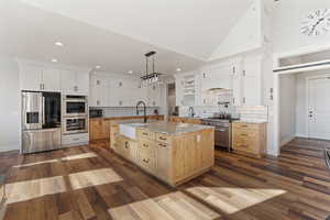 Kitchen featuring white cabinetry, sink, a center island with sink, and appliances with stainless steel finishes