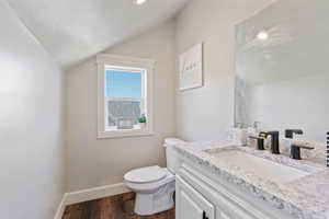 Bathroom with lofted ceiling, toilet, wood-type flooring, and vanity