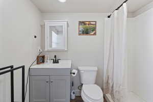 Bathroom with vanity, a shower with shower curtain, and toilet