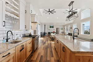 Kitchen featuring white cabinetry, stainless steel range, sink, and a large island with sink