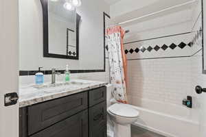 Full bathroom with tile walls, vanity, toilet, and shower / bath combo