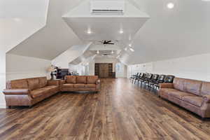 Living room featuring vaulted ceiling, dark hardwood / wood-style floors, ceiling fan, and a wall unit AC