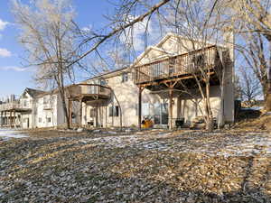 Snow covered back of property featuring a wooden deck