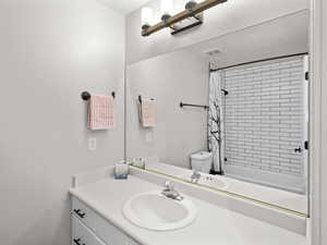 Full bathroom with vanity, toilet, and shower / bath combo with shower curtain