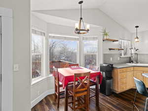 Dining area with lofted ceiling, sink, a notable chandelier, and dark hardwood / wood-style floors