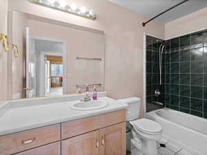 Full bathroom with vanity, a textured ceiling, toilet, and tiled shower / bath