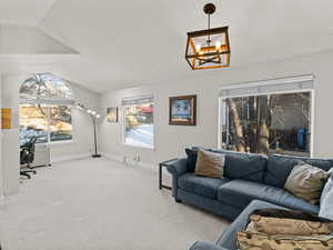 Carpeted living room with lofted ceiling and a chandelier