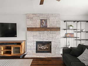 Living room with a stone fireplace, hardwood / wood-style floors, and ceiling fan