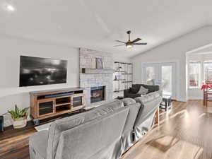 Living room featuring lofted ceiling, a fireplace, wood-type flooring, and french doors