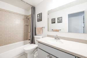 Full bathroom featuring toilet, vanity, and shower / bathtub combination with curtain