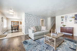 Living room with hardwood / wood-style flooring, an inviting chandelier, and a textured ceiling