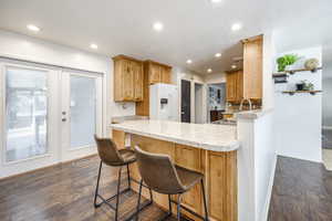 Kitchen featuring sink, white refrigerator with ice dispenser, kitchen peninsula, and a kitchen bar