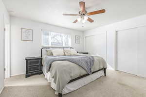 Carpeted bedroom featuring multiple closets and ceiling fan