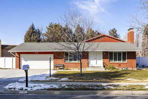 Single story home with a garage and a lawn