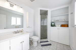 Bathroom featuring vanity, tile patterned floors, toilet, and walk in shower