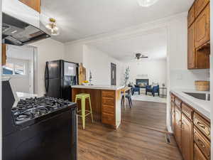 Kitchen featuring ceiling fan, backsplash, dark hardwood / wood-style floors, island range hood, and black appliances