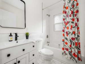 Full bathroom featuring vanity, tile walls, shower / bathtub combination with curtain, and toilet