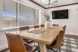 Dining room with a notable chandelier, crown molding, and wood-type flooring