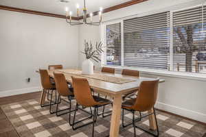 Dining space with crown molding, wood-type flooring, a chandelier, and a wealth of natural light