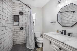 Bathroom featuring vanity, walk in shower, and toilet