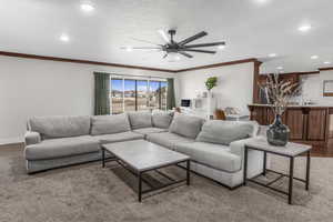 Living room featuring crown molding, a textured ceiling, and ceiling fan