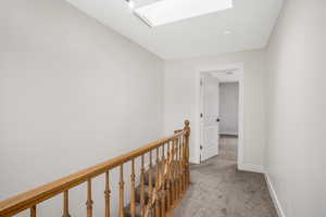 Hall with a skylight and light colored carpet