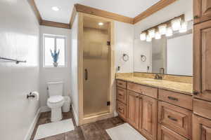 Bathroom featuring an enclosed shower, vanity, crown molding, and toilet