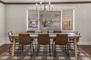 Dining space featuring dark hardwood / wood-style flooring, a notable chandelier, and crown molding