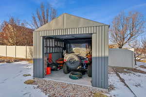 View of snow covered accessory garage for storage and toys