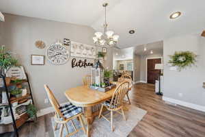 Dining space featuring lofted ceiling, hardwood / wood-style floors, and a notable chandelier