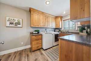 Washroom with sink, washer and clothes dryer, cabinets, and light wood-type flooring