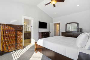 Carpeted bedroom featuring ceiling fan, lofted ceiling, and connected bathroom