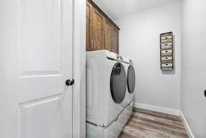 Laundry area featuring hardwood / wood-style flooring, cabinets, and washer and dryer