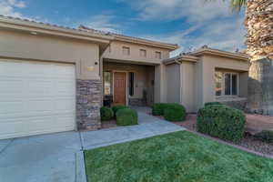 View of exterior entry with a garage and a yard