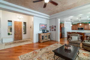 Living room featuring ceiling fan with notable chandelier and light hardwood / wood-style floors