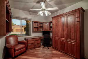 Office space with ceiling fan, built in desk, and light hardwood / wood-style flooring