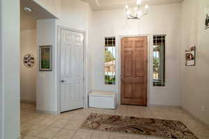 Entryway featuring light tile patterned flooring and a notable chandelier