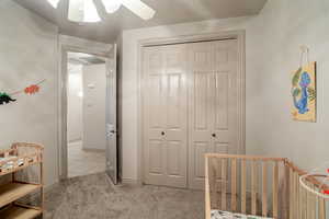 Bedroom with light carpet, ceiling fan, and a closet