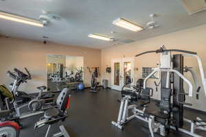 Exercise room featuring a textured ceiling, french doors, and ceiling fan