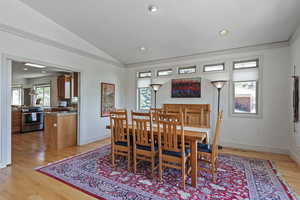 Dining area featuring ornamental molding, vaulted ceiling, and light hardwood / wood-style floors