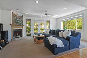 Living room with ceiling fan, ornamental molding, and a fireplace