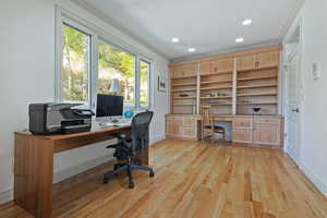 Home office with built in desk, ornamental molding, light hardwood / wood-style floors, and plenty of natural light