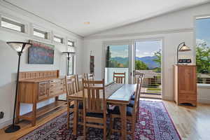 Dining room with a mountain view, vaulted ceiling, and light wood-type flooring