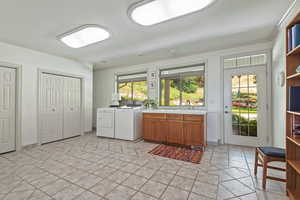 Laundry area with sink, ornamental molding, washing machine and dryer, and cabinets