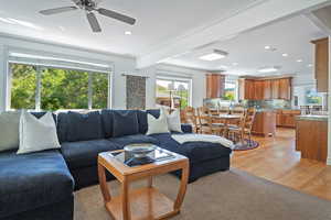 Living room featuring ceiling fan, ornamental molding, beam ceiling, and light wood-type flooring